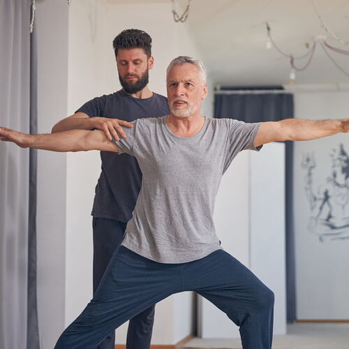 Aufnahme eines Mannes welcher unter Anweisungen des Trainers Pilates Übungen vollzieht.